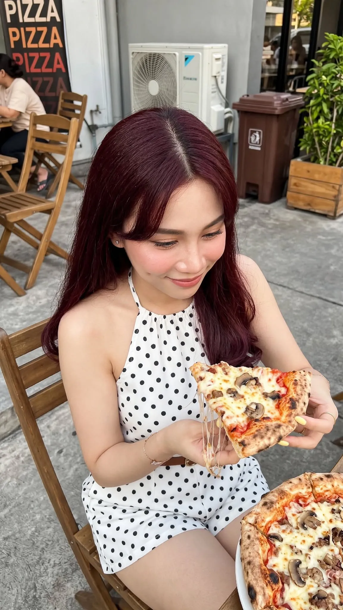 Young Woman Eating Pizza at an Outdoor Restaurant